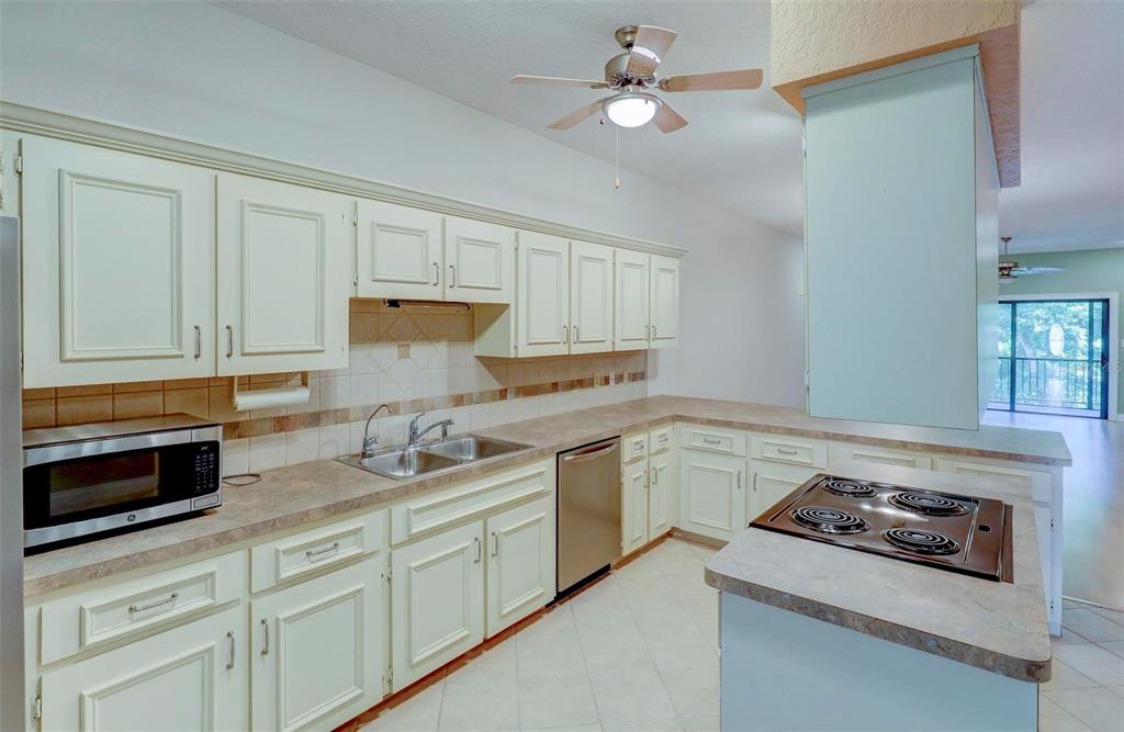 A kitchen with white cabinets, laminate countertops, a center island cooktop, and tile flooring — 7032 RIVER RUN BOULEVARD, WEEKI WACHEE, FL