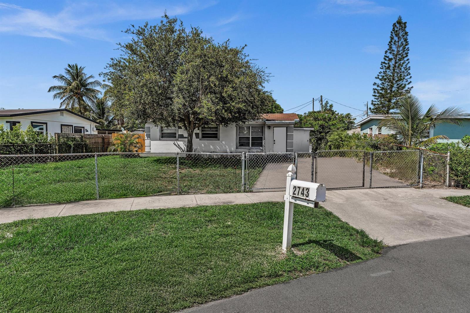 A single-story house with a fenced front yard and a driveway behind a chain-link gate — 2743 NW 2nd Street, Boynton Beach FL 33435, BOYNTON BEACH, FL