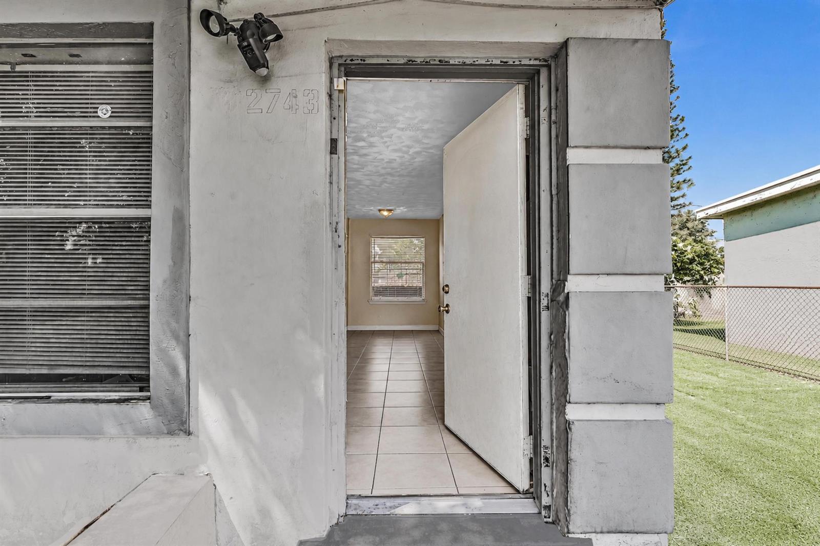 An open front door reveals a tiled living area with a window and ceiling light — 2743 NW 2nd Street, Boynton Beach FL 33435, BOYNTON BEACH, FL