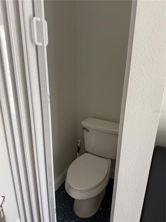 A toilet is situated in a small, enclosed room with a folding door — 6837 AMANDA VISTA CIRCLE, LAND O LAKES, FL
