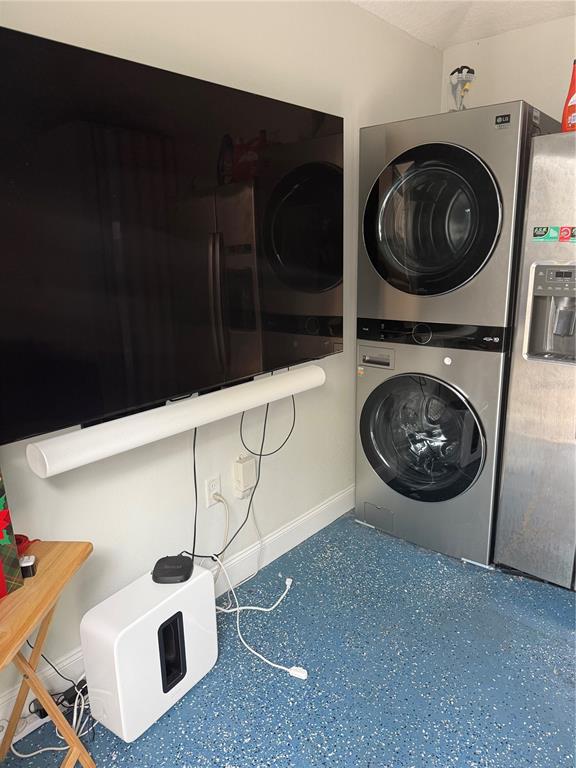 A wall-mounted television and soundbar are positioned next to a stacked washer and dryer unit — 6837 AMANDA VISTA CIRCLE, LAND O LAKES, FL