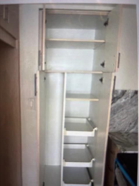 A tall, open pantry cabinet features upper shelves and lower pull-out drawers in a kitchen — 4164 Inverrary Drive # 702, Lauderhill FL 33319, LAUDERHILL, FL