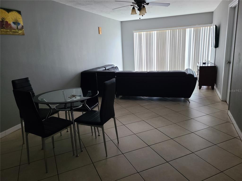 A dining area with a glass table and chairs sits before a living room sofa — 2763 WOODGATE LANE UNIT 204, SARASOTA, FL