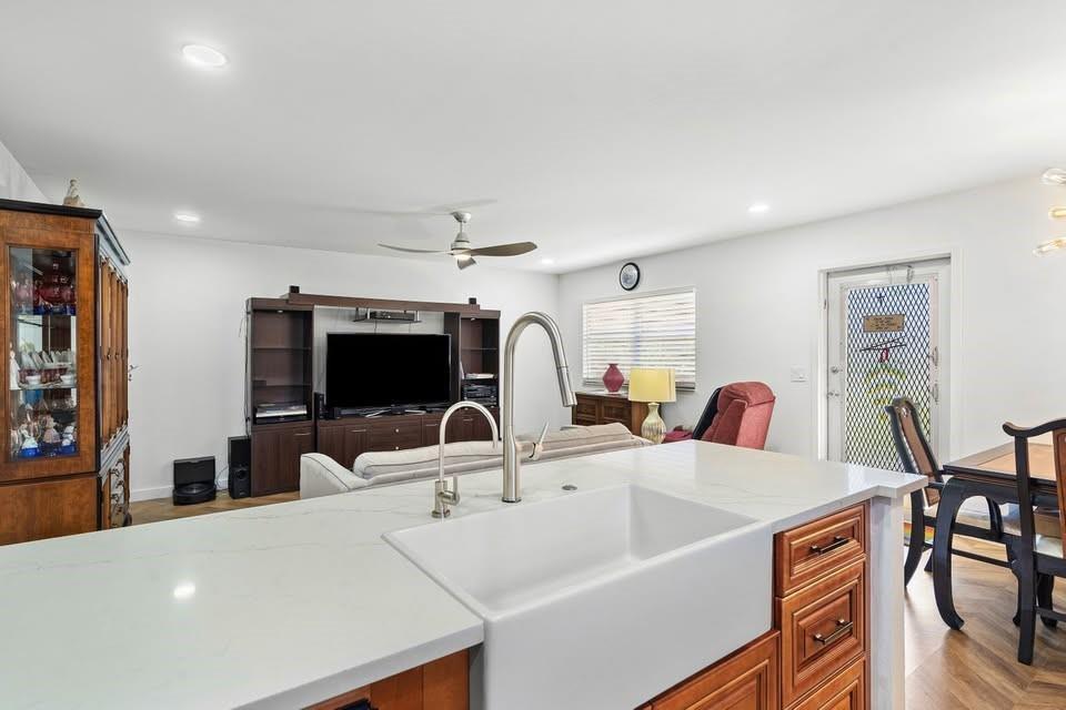 A kitchen island with a farmhouse sink overlooks a living room with a television console — 156 Seville, Delray Beach FL 33446, DELRAY BEACH, FL