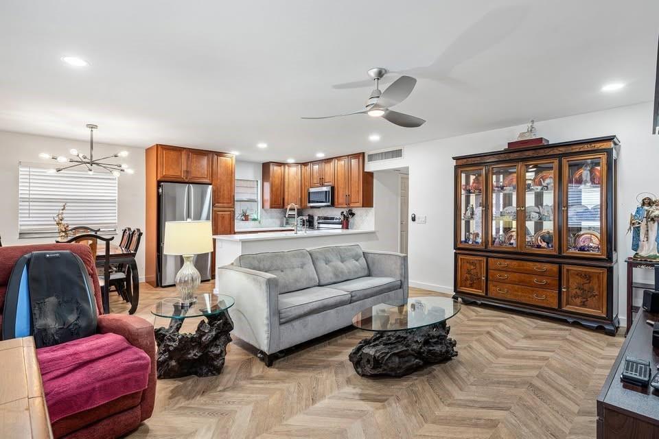 An open-concept living and dining area features wood herringbone flooring and a large china cabinet — 156 Seville, Delray Beach FL 33446, DELRAY BEACH, FL