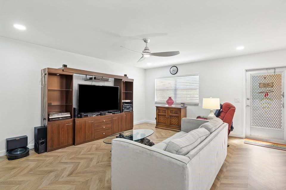 A living room features a large entertainment center, a grey sofa, and herringbone wood flooring — 156 Seville, Delray Beach FL 33446, DELRAY BEACH, FL