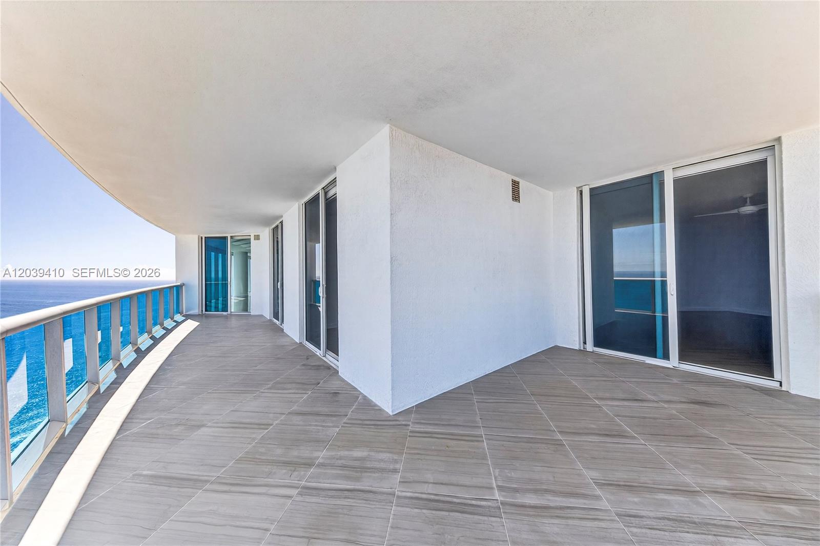 A spacious, tiled balcony features glass railings and sliding doors overlooking the ocean — 2711 S OCEAN DR # 3102, Hollywood FL 33024, HOLLYWOOD, FL