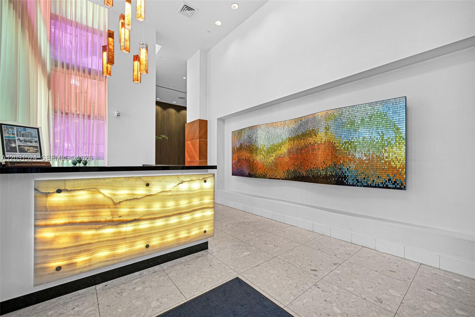 A modern lobby features a backlit stone reception desk and a large mosaic wall art piece — 3801 Collins Ave # 1102, Miami Beach FL 33140, MIAMI BEACH, FL