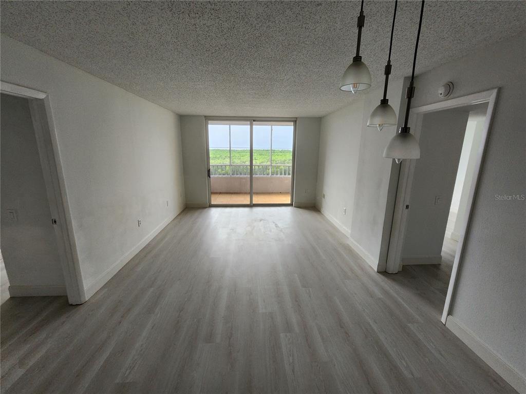An empty room with light wood-look flooring, white walls, and a sliding glass door to a balcony — 2333 FEATHER SOUND DRIVE UNIT A607, CLEARWATER, FL