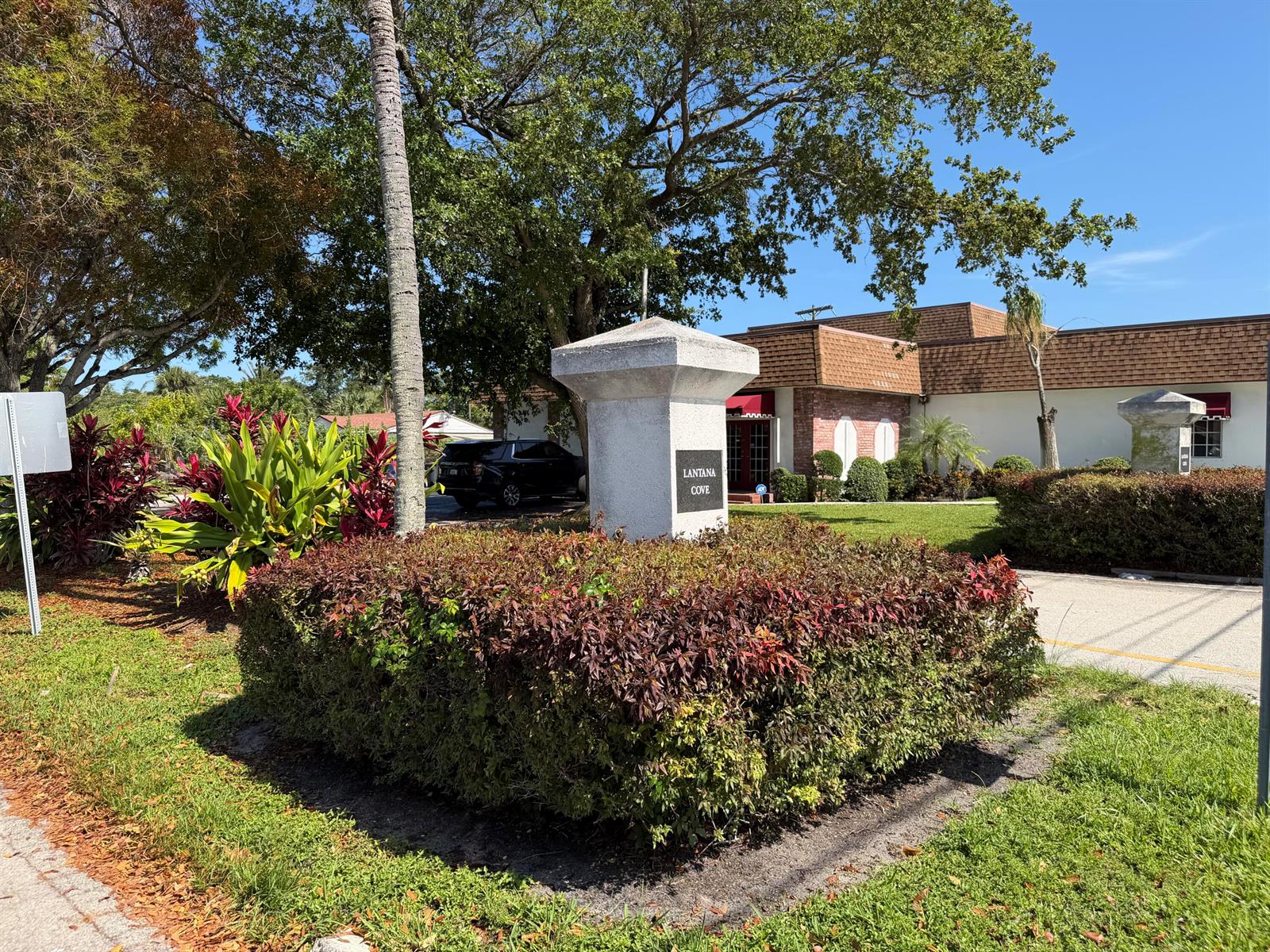 A stone monument sign for Lantana Cove sits in front of a building with landscaping — 112 Prospect Road, Lantana FL 33462, LANTANA, FL