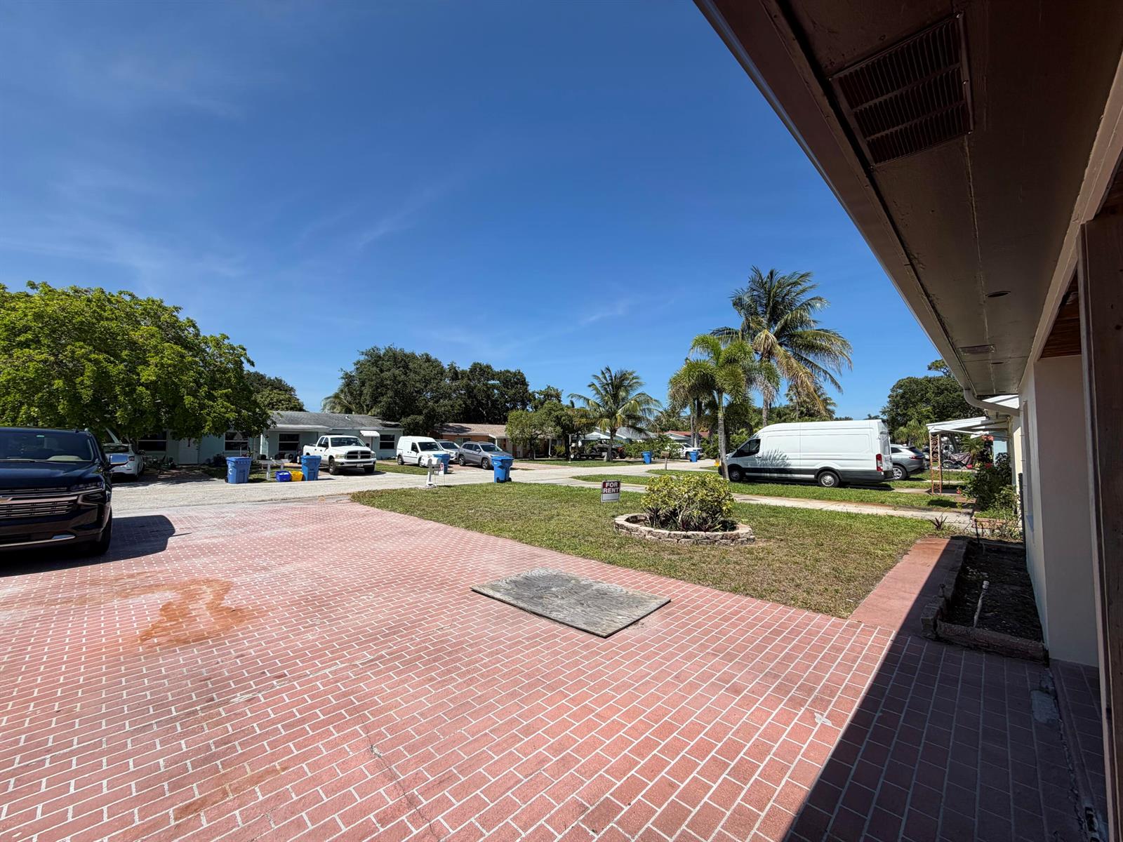 A brick driveway leads to a front yard with a palm tree and parked vehicles — 112 Prospect Road, Lantana FL 33462, LANTANA, FL