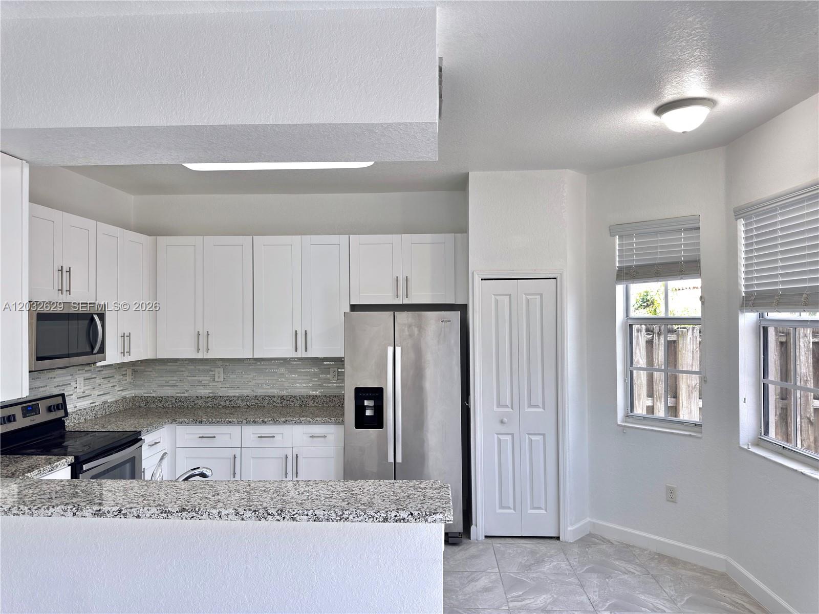 A kitchen features white cabinets, stainless steel appliances, granite countertops, and a tile floor — 7905 SW 120th Ave # 7905, Miami FL 33183, MIAMI, FL