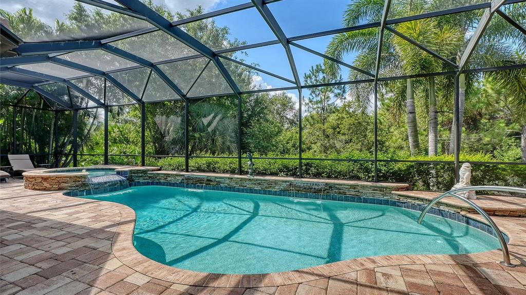 A screened-in swimming pool and spa feature stone accents and a brick paver deck — 7640 HADDINGTON COVE, LAKEWOOD RANCH, FL