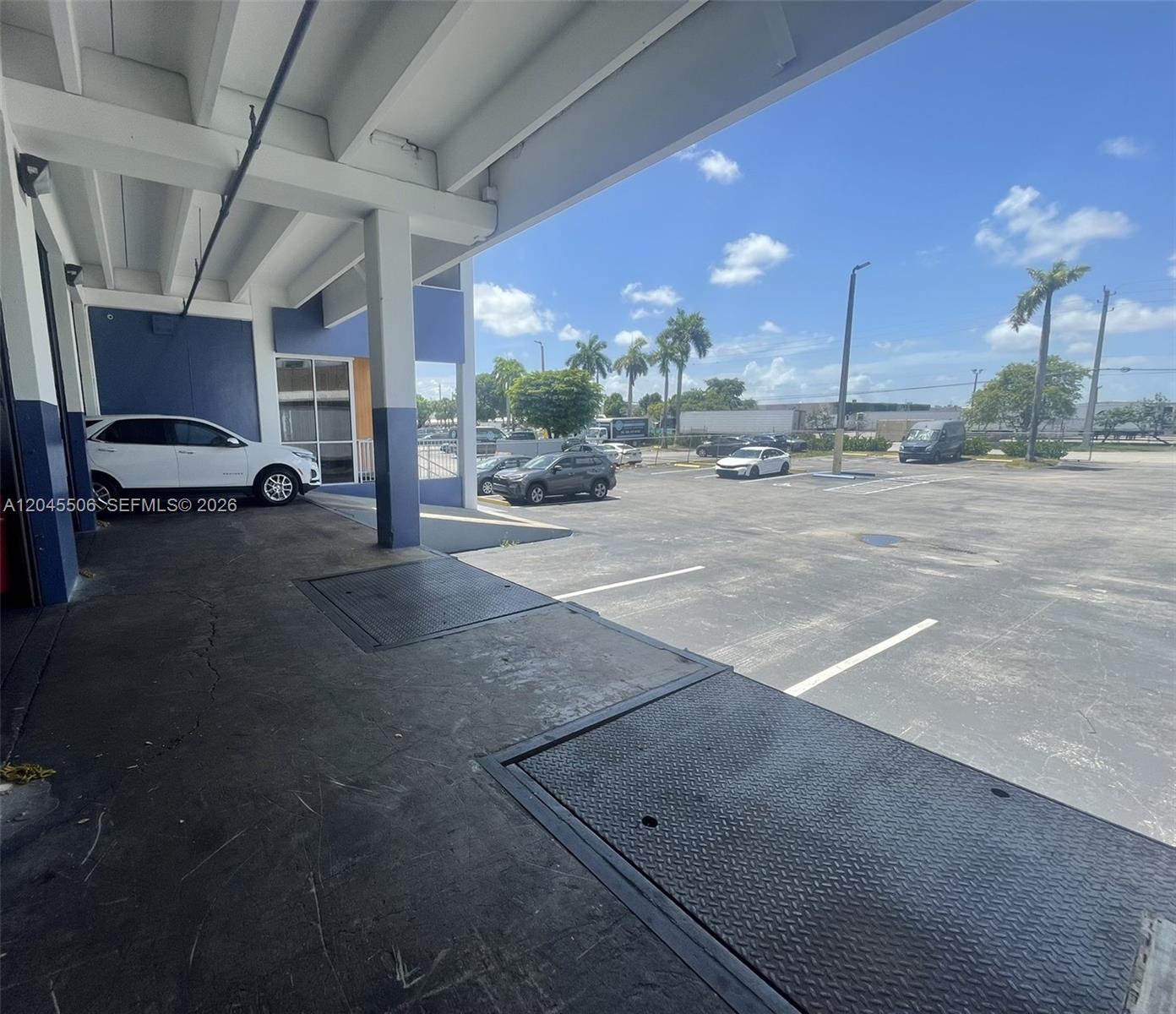 A concrete loading dock area overlooks an outdoor parking lot under a blue sky — FL