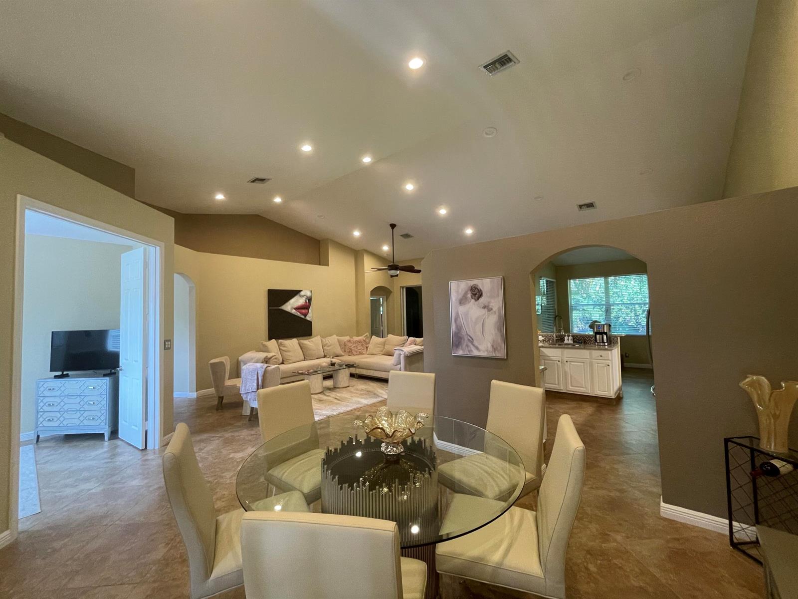 A dining area with a glass table sits in front of an open-concept living room — 16075 Sims Road # 203, Delray Beach FL 33484, DELRAY BEACH, FL