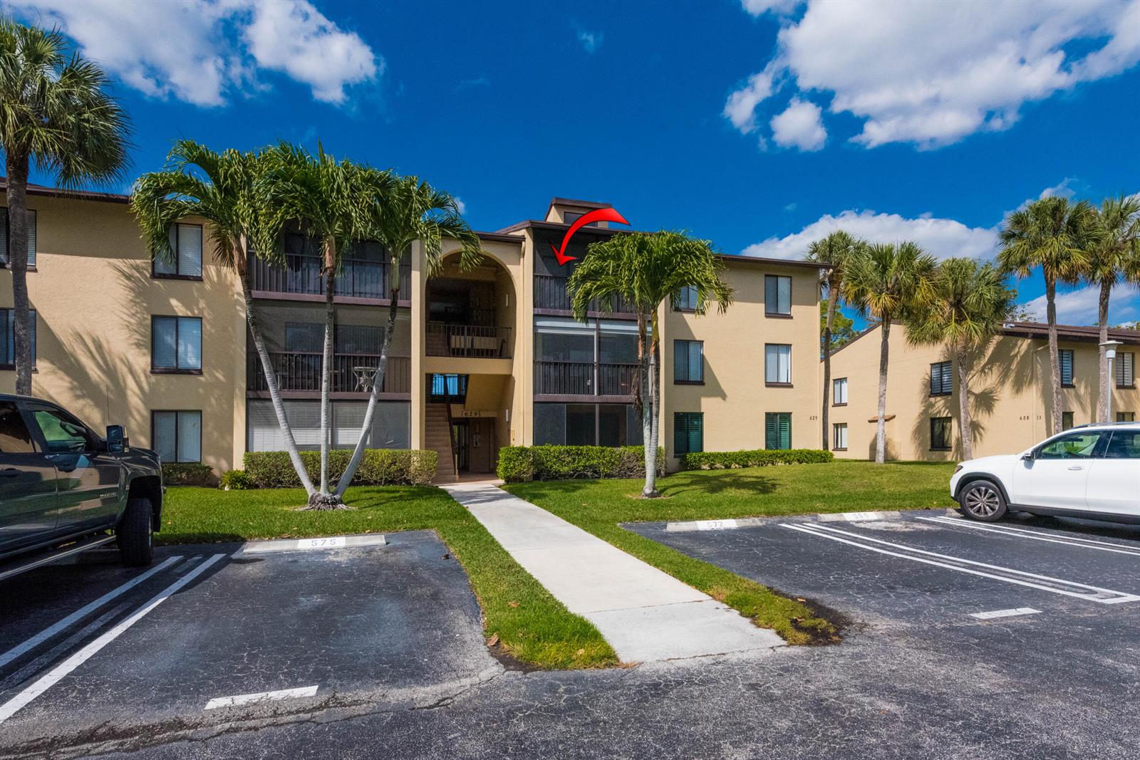 An exterior view of a three-story apartment building with a red arrow pointing to a balcony — 629 Sea Pine Way # D3, FL 33415, FL