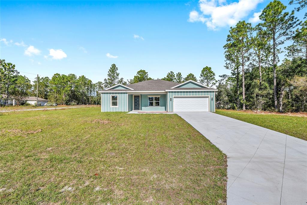 A light blue single-story house with a white garage and a concrete driveway — 9370 N DEL RIO WAY, CITRUS SPRINGS, FL