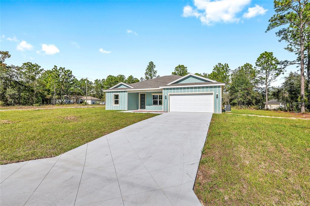 A single-story light blue house with a white garage and a concrete driveway — 9370 N DEL RIO WAY, CITRUS SPRINGS, FL