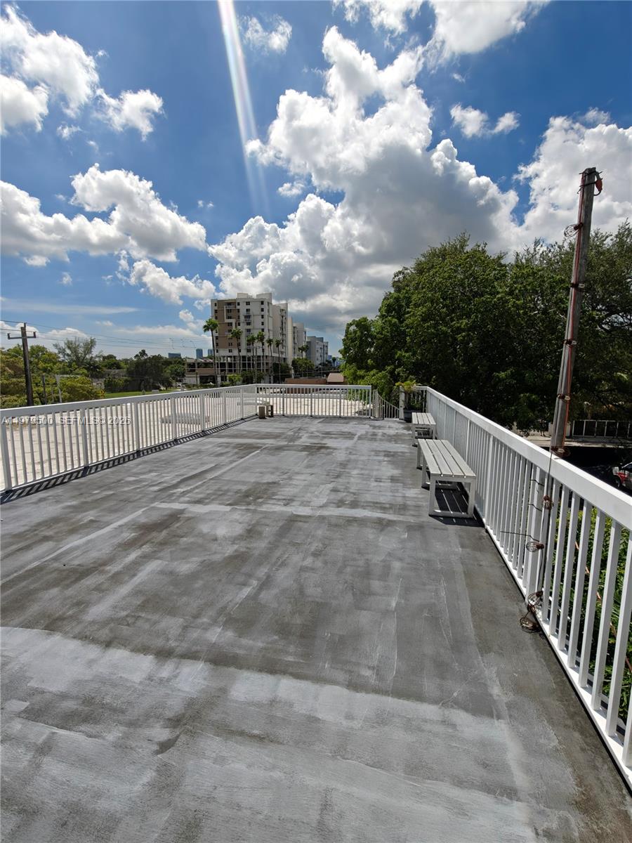 An outdoor rooftop terrace features a gray concrete floor, white railings, and two wooden benches — 5900 NW 2nd Ave Suite 1, Miami FL 33127, MIAMI, FL