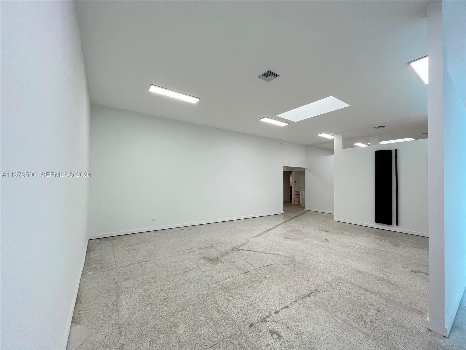 An empty room with white walls, concrete flooring, and multiple ceiling light fixtures — 5900 NW 2nd Ave Suite 1, Miami FL 33127, MIAMI, FL