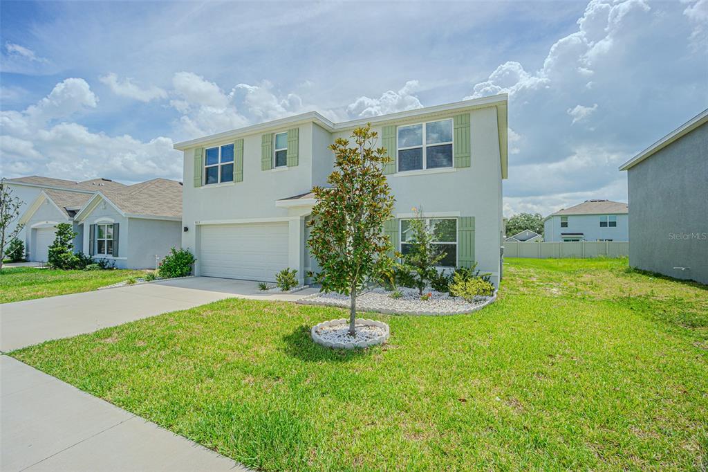 A two-story suburban house with light-colored stucco, green shutters, and a front yard tree — 9213 MISSION BAY PL, TEMPLE TERRACE, FL