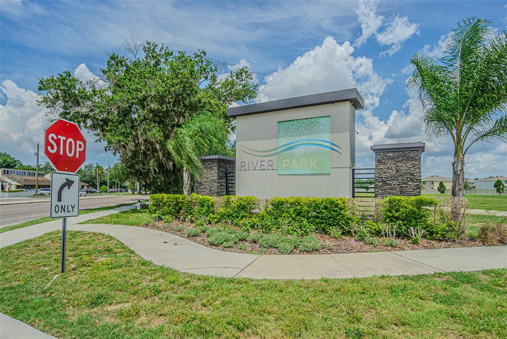 A stone and stucco monument sign for River Park stands near a stop sign — 9213 MISSION BAY PL, TEMPLE TERRACE, FL