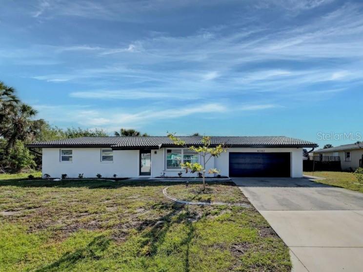A single-story white house with a dark tiled roof and an attached two-car garage — 4342 EWING CIRCLE, PORT CHARLOTTE, FL