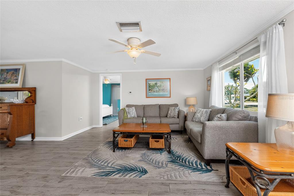 A living room features gray sofas, a wooden coffee table, and a palm-patterned area rug — 650 LEACH STREET, ENGLEWOOD, FL