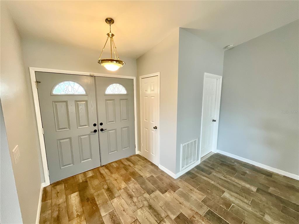 An entryway features double gray doors, light gray walls, and wood-look tile flooring — 2991 VALENCIA LANE E, PALM HARBOR, FL