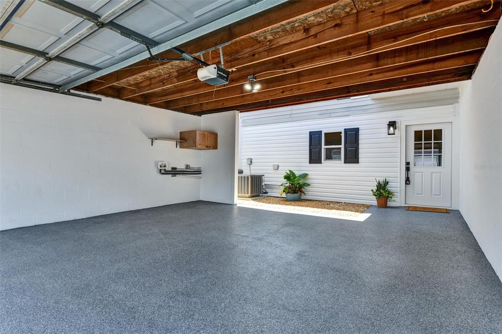 A garage with a speckled epoxy floor, exposed wooden ceiling joists, and a white door — 11906 DIETZ DRIVE UNIT 22, TAMPA, FL