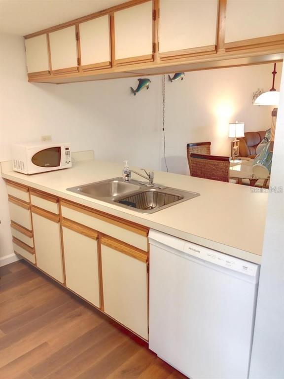A kitchen features light-colored cabinets, a white dishwasher, a double sink, and a microwave — 4056 OAKVIEW DRIVE UNIT E7, PORT CHARLOTTE, FL