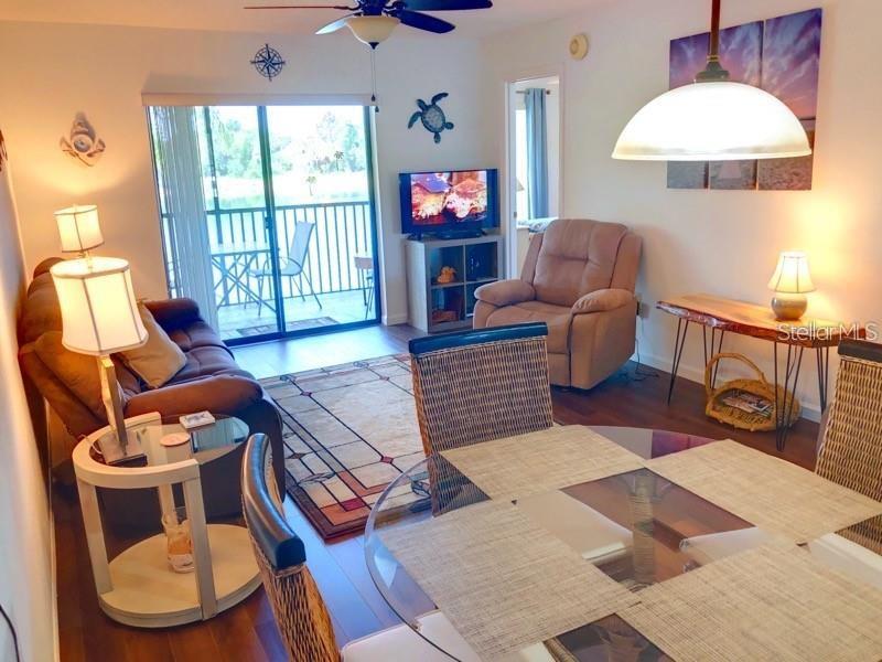 This living and dining area features a brown sofa, a recliner, and a glass-topped table — 4056 OAKVIEW DRIVE UNIT E7, PORT CHARLOTTE, FL