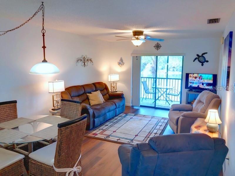 A living room features a brown sofa, a recliner, a dining set, and a balcony view — 4056 OAKVIEW DRIVE UNIT E7, PORT CHARLOTTE, FL