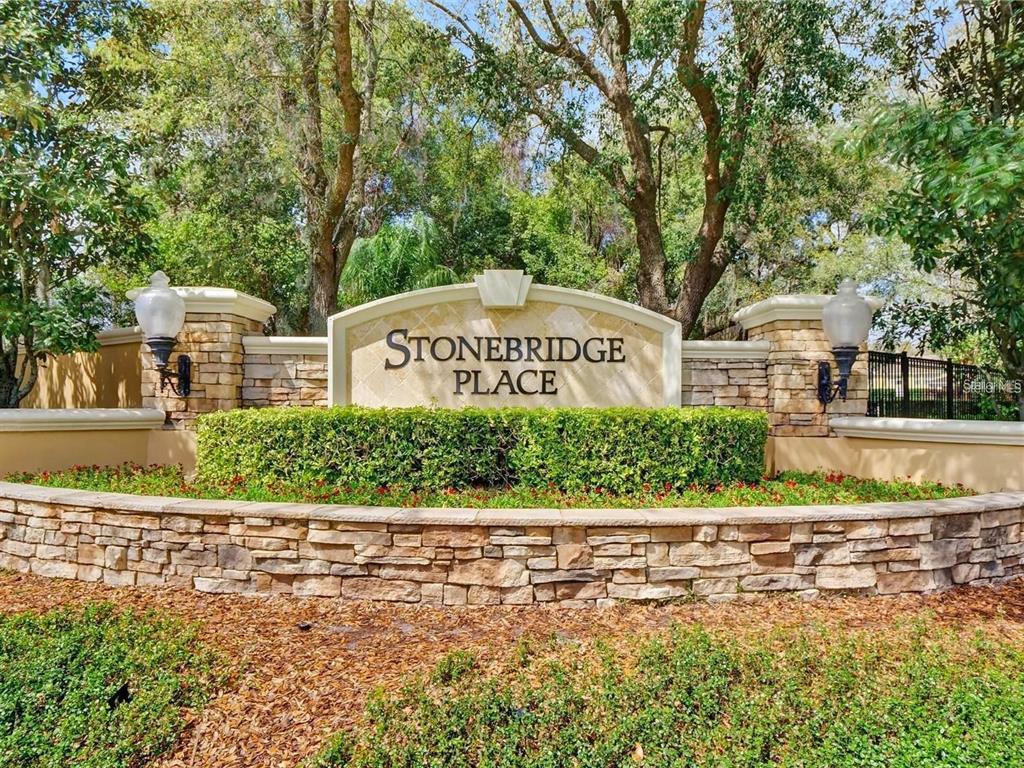 A stone and stucco monument sign for Stonebridge Place sits behind a manicured hedge — 3190 DANTE DRIVE UNIT 102, ORLANDO, FL