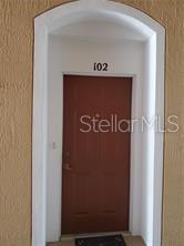 A brown front door with the number 102 above it set in an arched frame — 3190 DANTE DRIVE UNIT 102, ORLANDO, FL