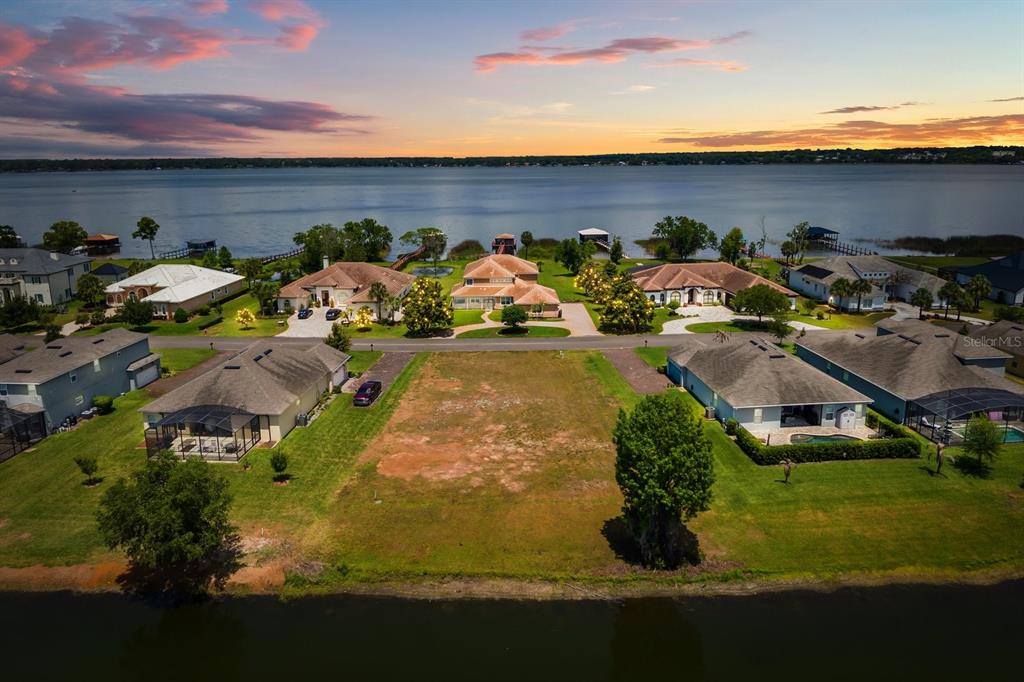 An aerial view shows a vacant residential lot situated between two houses near a lake — LOT H-19 ISLAND CLUB DRIVE, TAVARES, FL