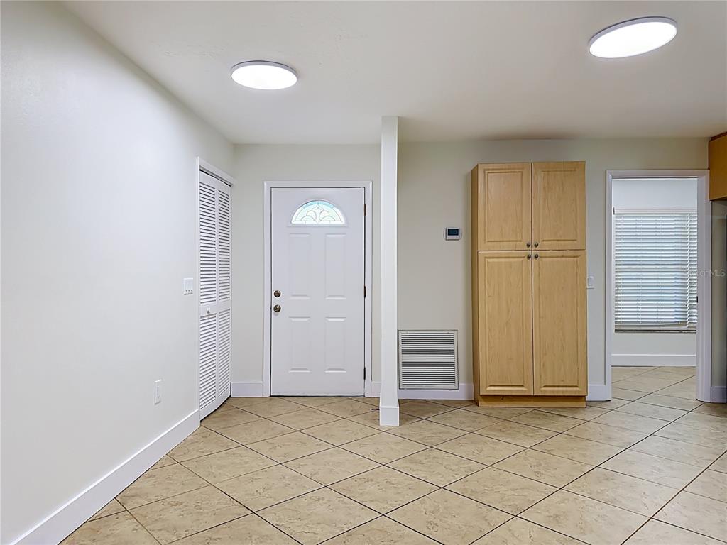 An interior view shows a tiled room with a white door, closet, and wooden cabinet — 2103 162ND STREET E, BRADENTON, FL
