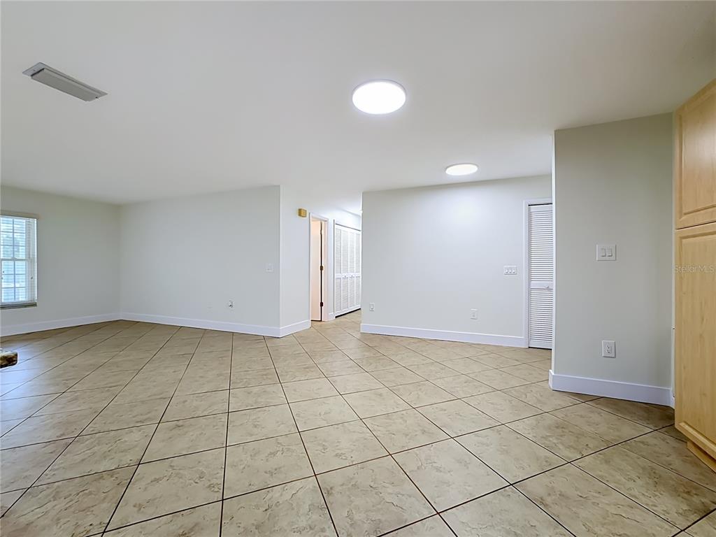 An empty room features light-colored tile flooring, white walls, recessed lighting, and louvered closet doors — 2103 162ND STREET E, BRADENTON, FL