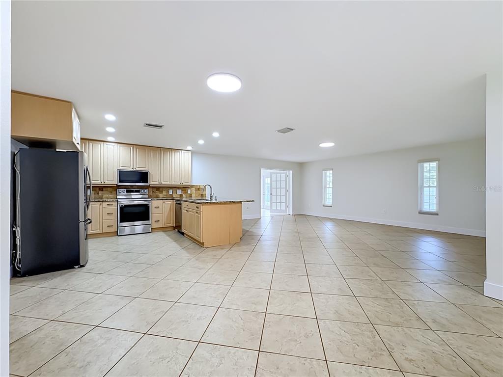 A spacious, open-concept kitchen and living area features light wood cabinets and tile flooring — 2103 162ND STREET E, BRADENTON, FL
