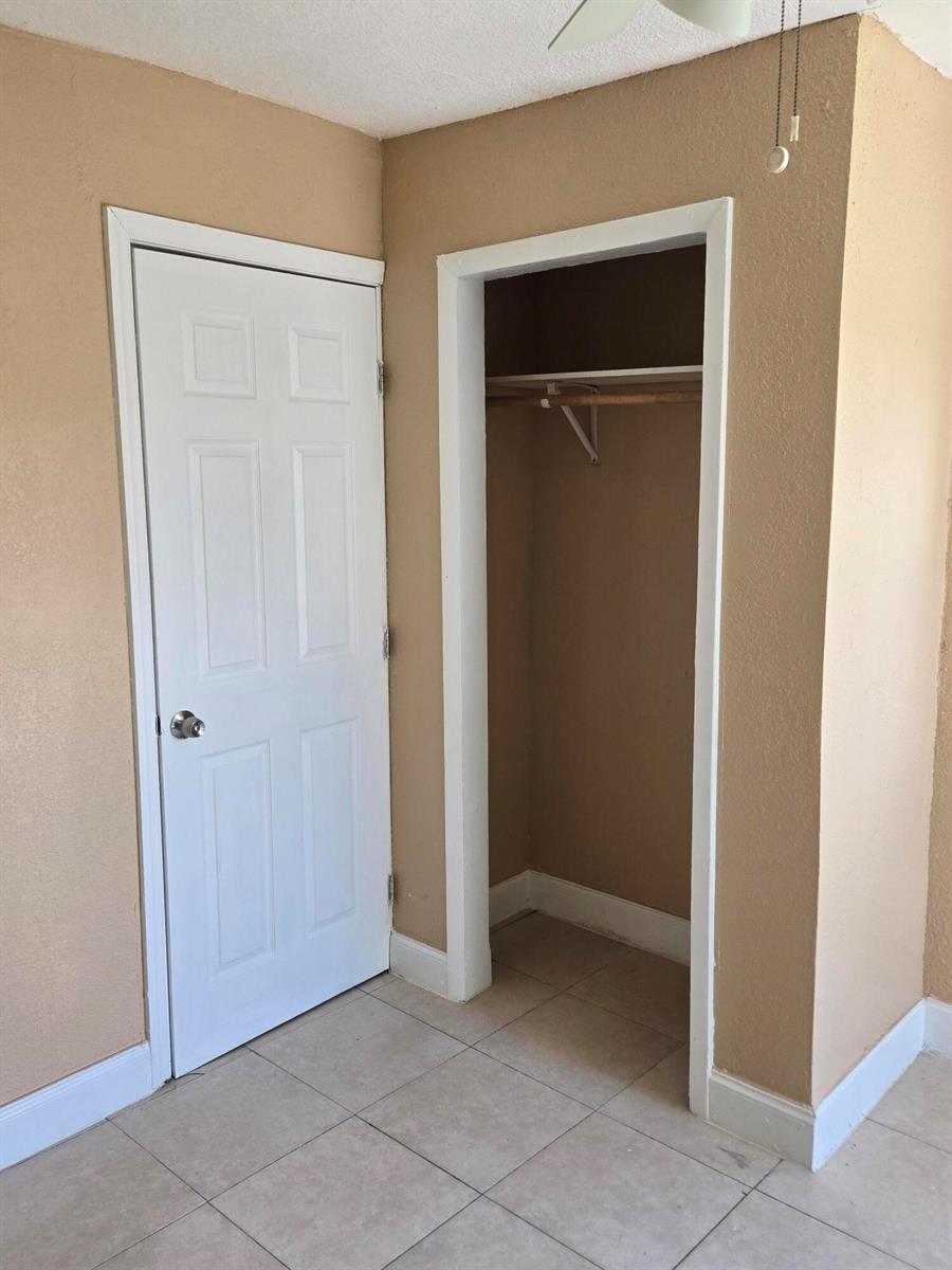 A room features tan walls, tile flooring, a closed white door, and an open closet — 815 Silver Beach Road # B, Lake Park FL 33403, LAKE PARK, FL