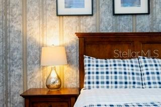 A bedroom features a wooden headboard, a plaid pillow, and a lamp on a nightstand — 2959 BANANA PALM DRIVE, KISSIMMEE, FL