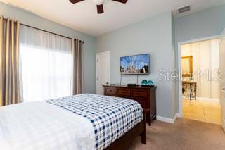 A bedroom features a bed with a plaid comforter, a wall-mounted television, and a doorway — 2959 BANANA PALM DRIVE, KISSIMMEE, FL