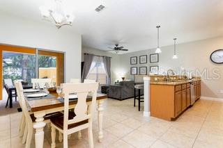 A dining area with a wooden table and chairs sits adjacent to an open kitchen — 2959 BANANA PALM DRIVE, KISSIMMEE, FL