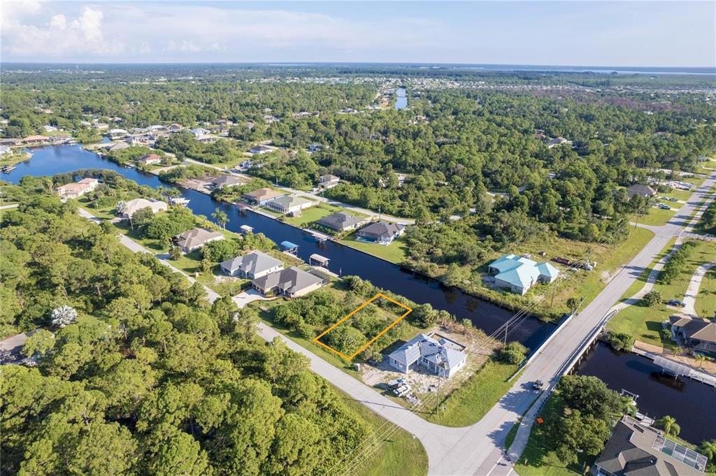 An aerial view shows a vacant, rectangular waterfront lot outlined in orange next to a house — 14292 KAY LANE, PORT CHARLOTTE, FL