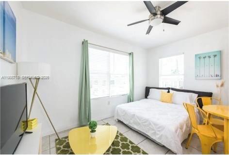 A bedroom features a bed with white bedding, a yellow table, and a ceiling fan — 7326 Collins Ave # 208, Miami Beach FL 33141, MIAMI BEACH, FL