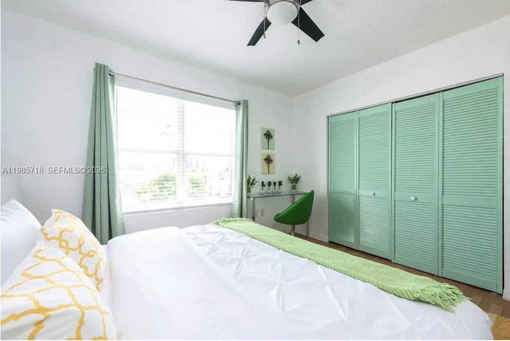 A bedroom features a white bed, mint green louvered closet doors, and a small desk area — 7326 Collins Ave # 208, Miami Beach FL 33141, MIAMI BEACH, FL