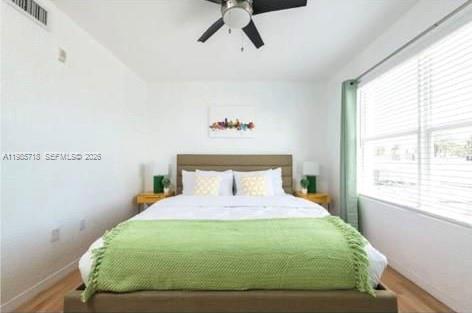 A bedroom features a bed with a green throw blanket, two nightstands, and a ceiling fan — 7326 Collins Ave # 208, Miami Beach FL 33141, MIAMI BEACH, FL