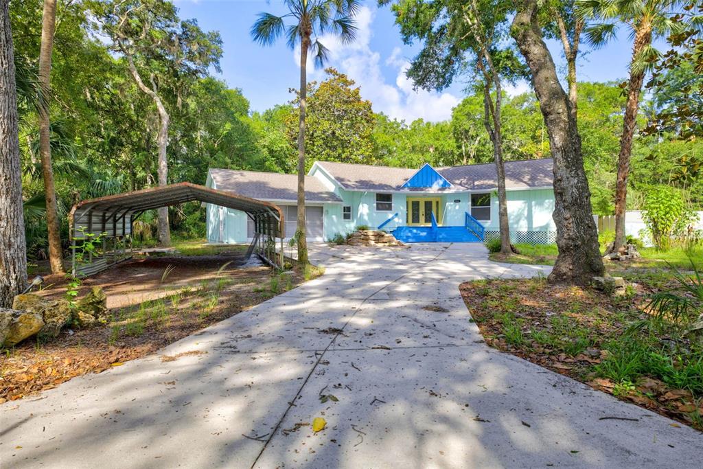 A light blue house with a metal carport and a concrete driveway surrounded by trees — 4586 S FLAMBEAU LOOP, HOMOSASSA, FL