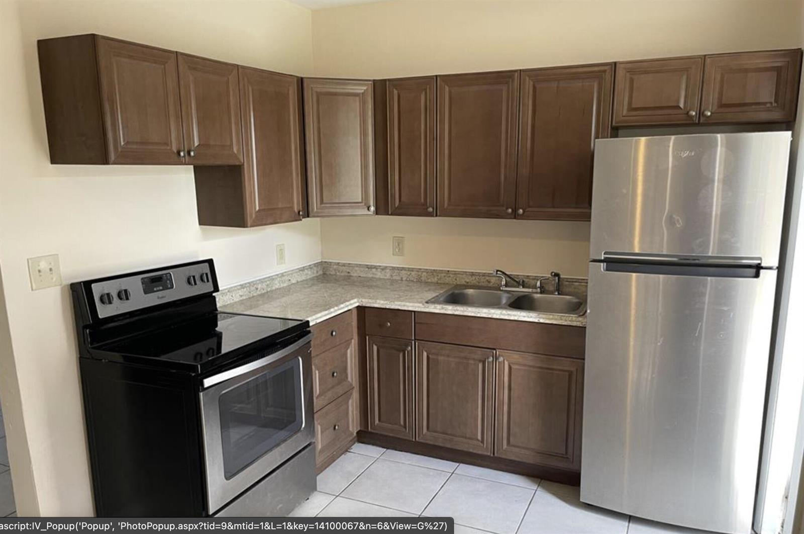 A kitchen features brown cabinets, stainless steel appliances, a double sink, and light-colored countertops — 1328 Lee Street, Delray Beach FL 33444, DELRAY BEACH, FL