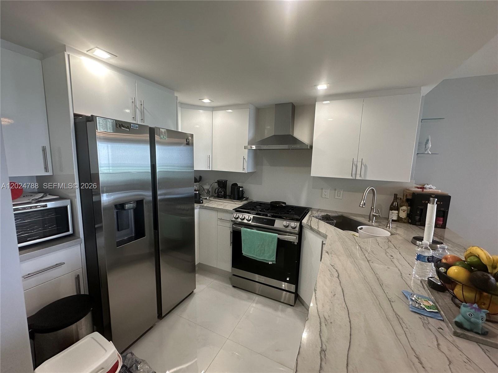 A modern kitchen features white cabinets, stainless steel appliances, and a marble-patterned countertop — 2030 S Ocean Dr # 916, Hallandale Beach FL 33009, HALLANDALE BEACH, FL